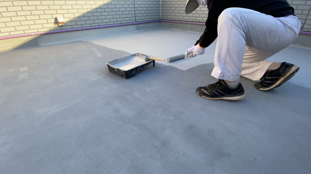 「バルコニーのウレタン防水塗装作業。ローラーで塗布するDIYリフォームの工程写真」