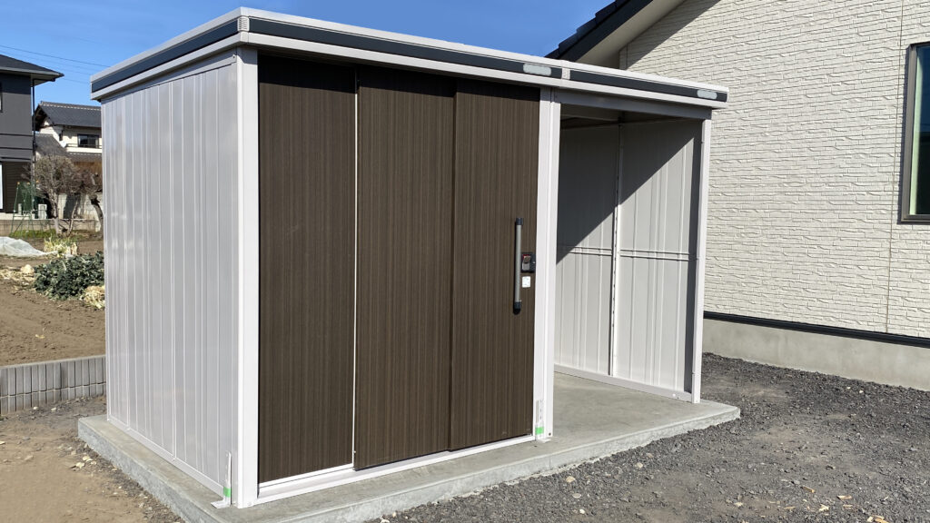 「住宅の庭に設置された物置と自転車置き場。新築住宅の外構設備写真」