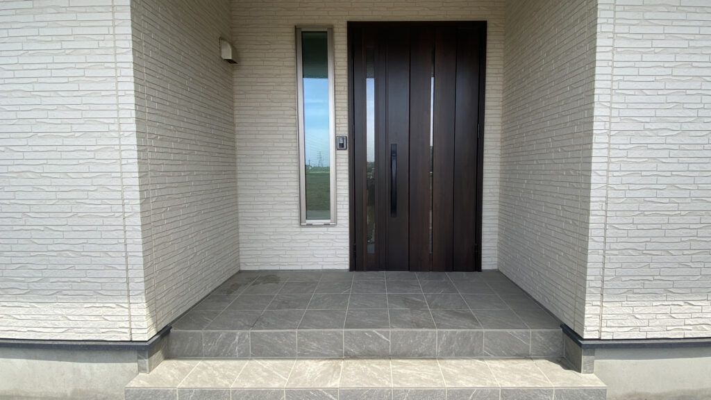 「新築住宅の玄関ポーチ。玄関タイルと玄関ドアの外観が分かる住宅・DIY向け写真」